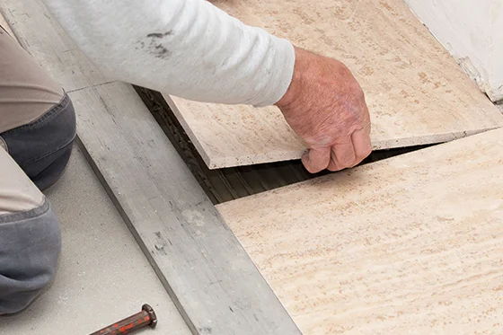 Person verlegt Fliesen mit Werkzeug